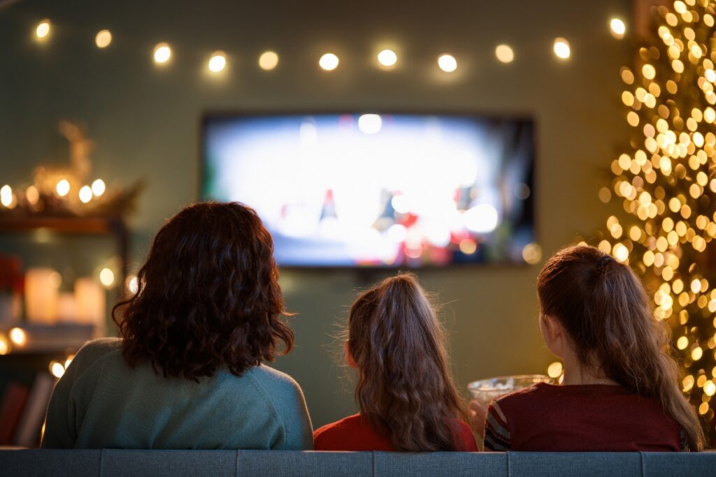 Mother and 2 kids watching a movie at home.