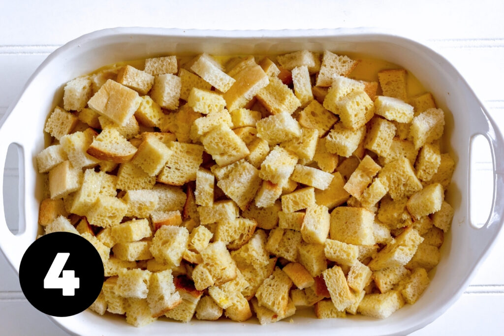 Cubes of bread in a casserole dish with a custard mixture filled halfway up the dish.