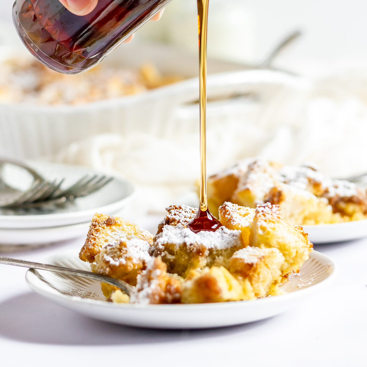 Syrup pouring over a plated serving of French toast casserole.