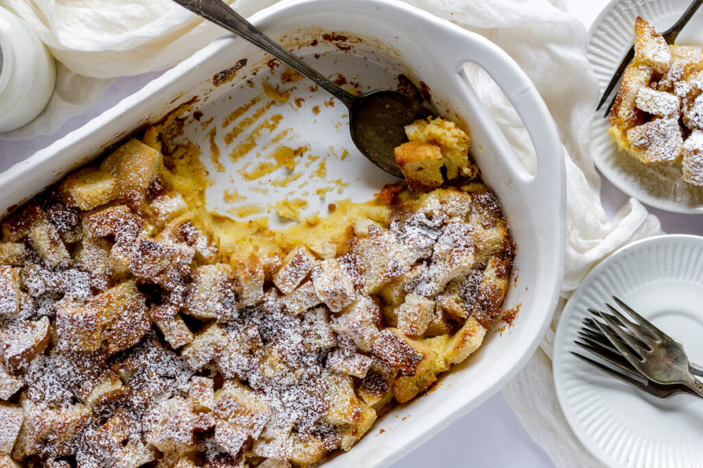 French toast casserole with a browned top and soft creamy interior and a scoop taken out of the corner of the casserole dish.